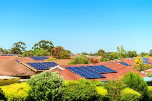 In this picture, under the blue sky and white clouds, there is a red tile roof. The house is surrounded by lush green trees, presenting a vibrant and lively scene. Installed with eco-friendly photovoltaic panels, it generates green energy and provides the residents with fresher air.